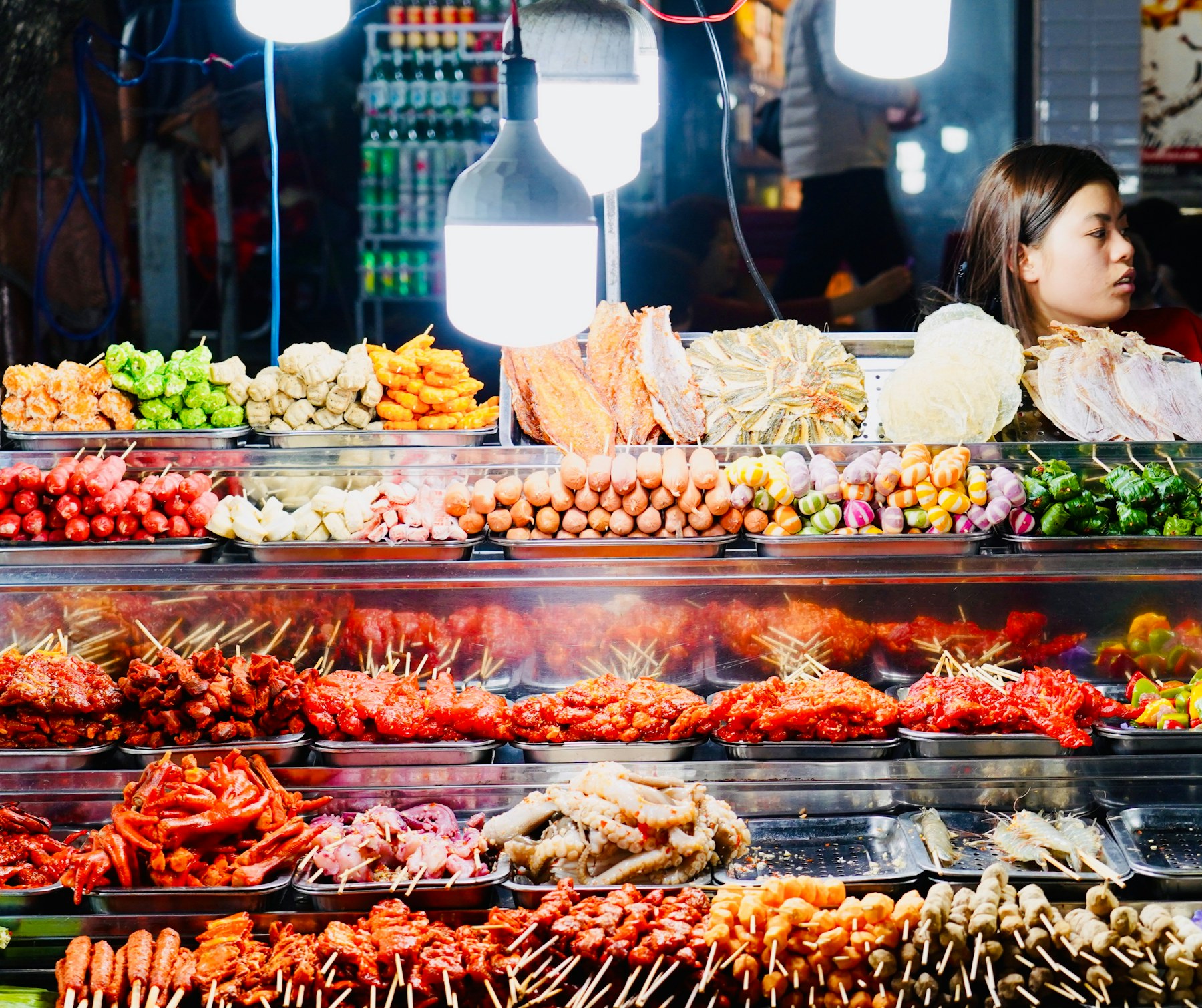 Skewers cooking over a glowing market grill